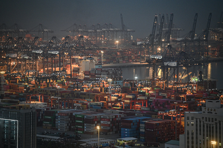 Night view of a busy shipping port in China with numerous containers and cranes.